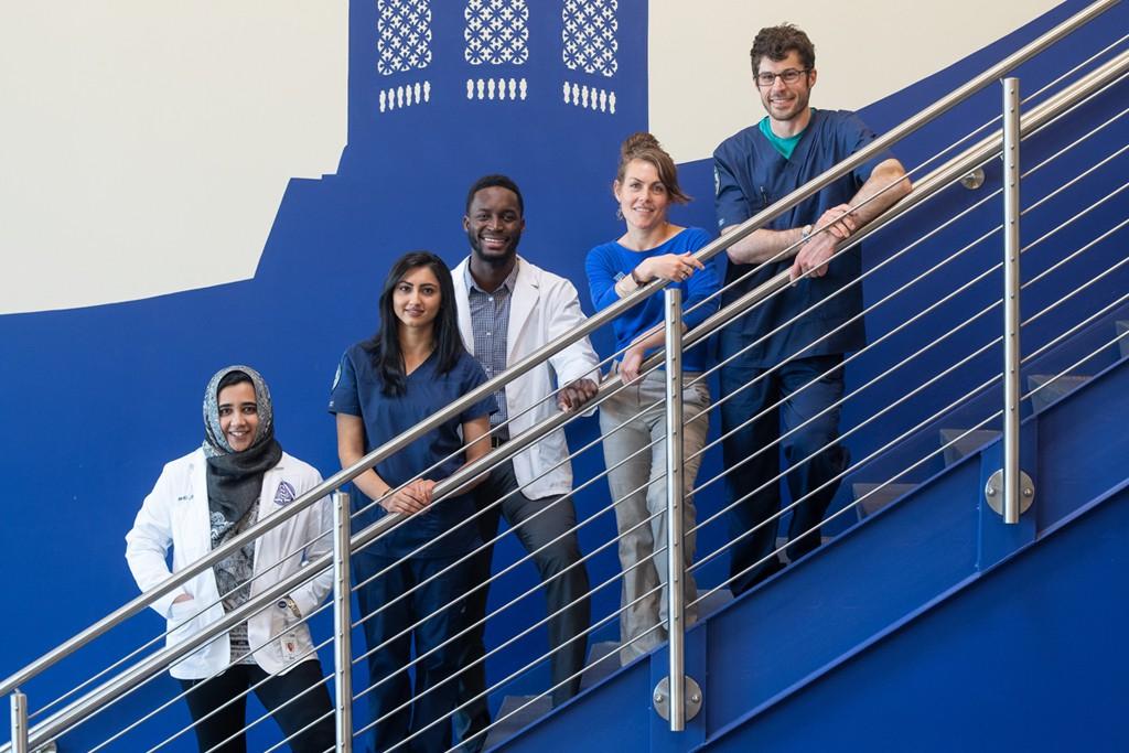 Five U N E health professions students pose together on a stair case